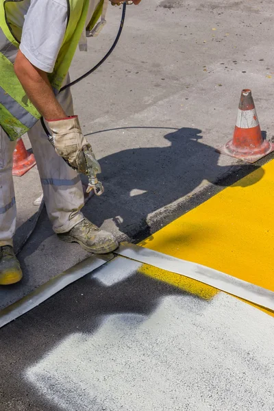 Arbeiter Hand hält industrielle Airless-Spritzpistole und Farbstreifen — Stockfoto