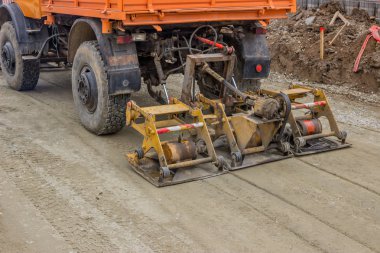  truck compacting gravel at road construction site clipart