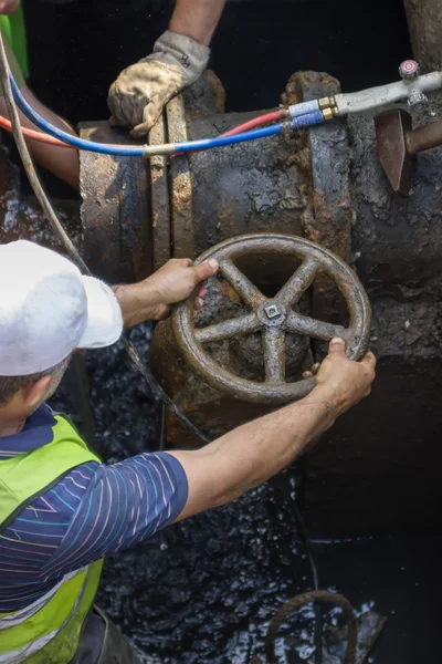 Industrial worker turning a valve on a large pipe — Stock Photo, Image