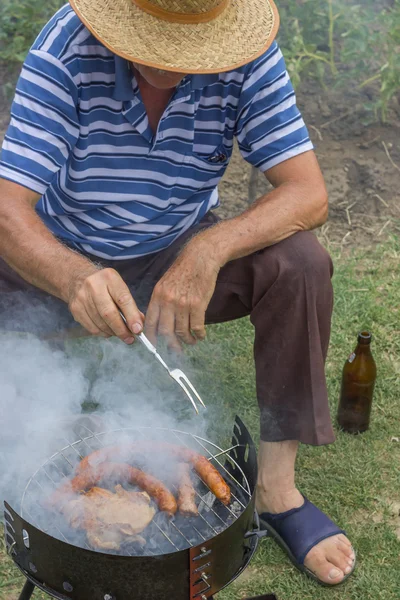 Homem sênior com um chapéu de palha em um churrasco — Fotografia de Stock