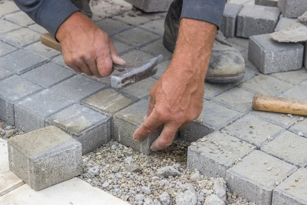 Mãos de trabalhadores que colocam pavers tijolo de concreto — Fotografia de Stock