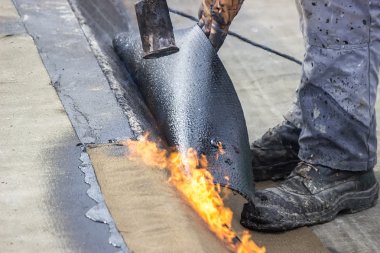 Worker heating and melting bitumen felt 3 clipart