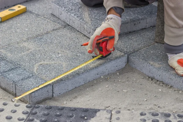 Paver misura lo spazio irregolare per la posa di mattoni di cemento — Foto Stock