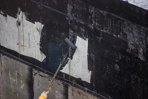 Impermeabilización, pintura de trabajadores pared de hormigón exterior con alquitrán i — Foto de Stock