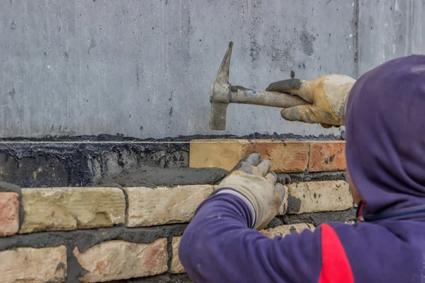 Using mason hammer to tap brick into position — Stock Photo, Image