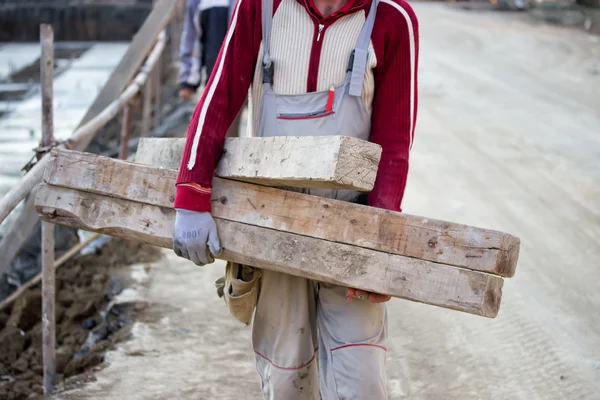 Trabajador que lleva viga de madera — Foto de Stock