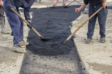 Asphalt workers with shovels patching asphalt clipart