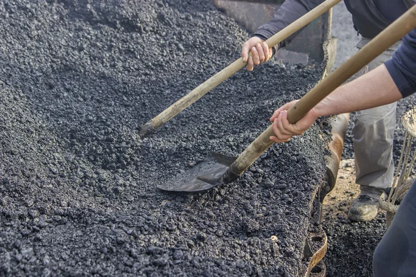 Asphalt workers with a shovel filling wheelbarrow with asphalt 3 — Stock Photo, Image