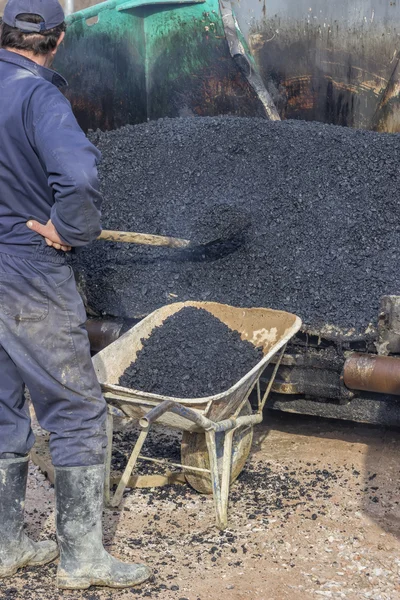 Trabajadores de asfalto con una carretilla de llenado de pala con asfalto —  Fotos de Stock