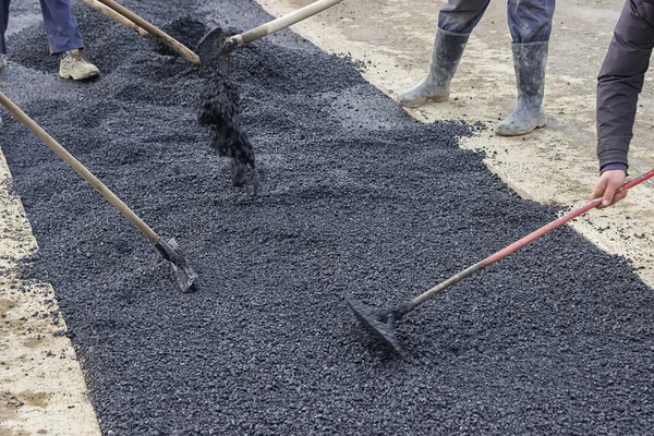 Road construction crew used shovels to scatter more asphalt — Stock Photo, Image