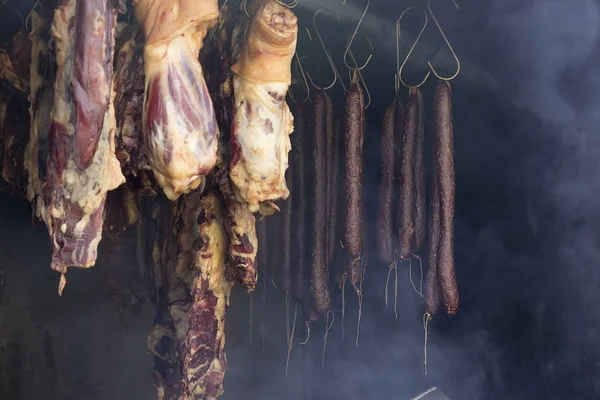 Meat and sausages hanging in smokehouse — Stock Photo, Image