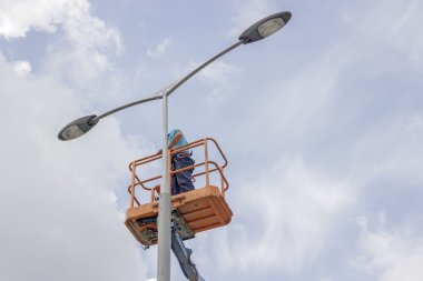worker in lift bucket repair street light pole clipart