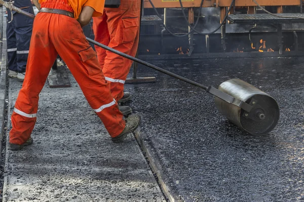 Obrero empujando rodillo de mano para pavimentación de asfalto masivo —  Fotos de Stock