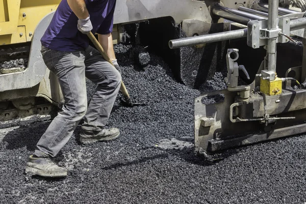 Worker using shovel and spread asphalt to ensure maximum coverag — Stock Photo, Image