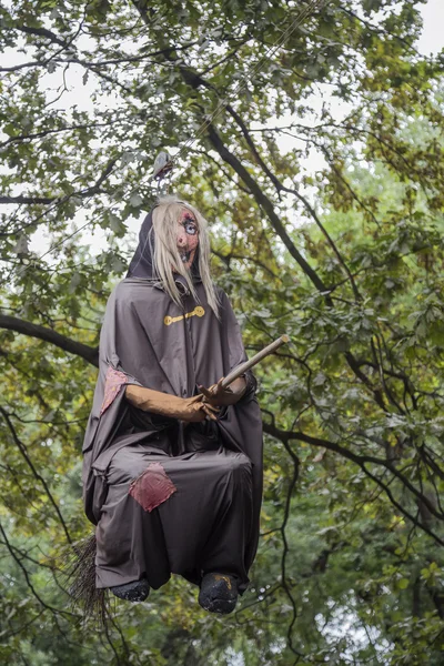 Кукла-ведьма летит на метле в лесу — стоковое фото