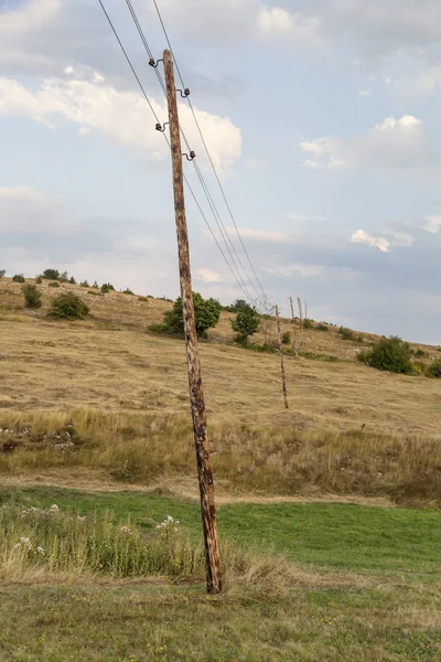 Pólos elétricos de madeira inclinados com fios — Fotografia de Stock