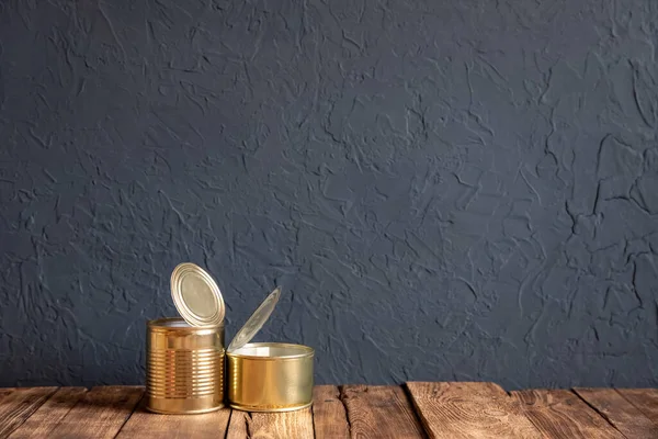 Two empty Golden tin cans on the wooden table. The grunge style. Space for text.
