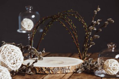 Paskalya bahar kompozisyonu, boş bir platform, kemer şeklinde söğüt dalları, ahşap bir masanın üzerindeki cam bir saat içinde rattan beyaz toplar..