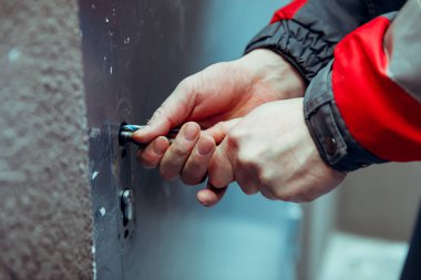 Hırsız, yankesicilerle ön metal kapıyı kırıyor. Doğaçlama aletler. Eller yakın plan..