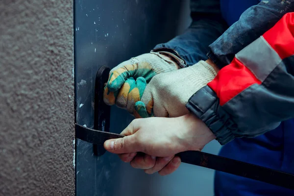 Hırsızlar, yankesicilerle ön metal kapıyı kırıyorlar. Doğaçlama aletler. Eller yakın plan..