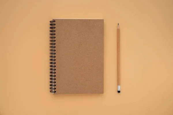 Top View Brown Closed Spiral Blank Paper Cover Notebook Pencil — Stock Photo, Image