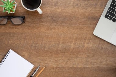Ahşap ofis masasının üstünde klavye, defter ve diğer ofis malzemeleriyle dolu kahve fincanı var. İş ve finans kavramı. Çalışma yeri, boş kopya alanı olan düz uzanma.