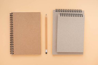 Kahverengi, sarmal, boş, mavi arka planda, kalem izole edilmiş not defterinin üstündeki üç okul kitabının üst görüntüsü bir model tasarlamak için. Eğitim ve iş konsepti. düz yat