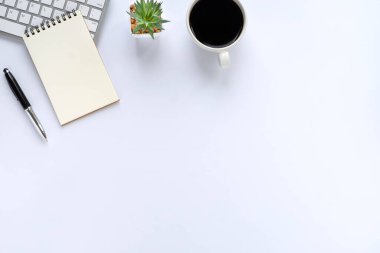 Klavyeli beyaz ofis masası, defter ve kahve fincanı diğer ofis malzemeleriyle dolu. İş ve finans kavramı. İşyeri, boş fotokopi alanı olan düz bir yer. Üst görünüm