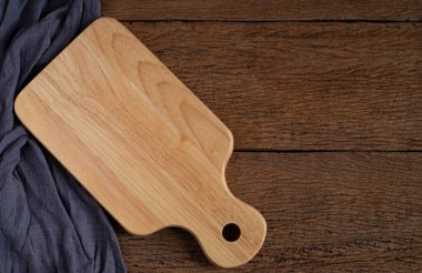 Ahşap kesim tahtasının üstünde tahta arka planda önlük var. Kopyalama alanı ile asılı olan boş tahta kesme tahtası ve delik.