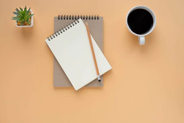 Top view of open school notebook with blank pages and pencil with coffee cup on brown background. Flat lay, creative workspace office. Business or education concept with copy space.