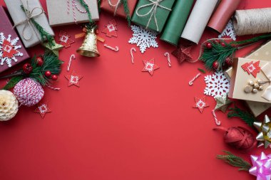 Noel tatili arkaplanının üstündeki en iyi manzara. Kırmızı arka planda köknar dalları, kurdele, fiyonk ve hediye kutusu süslemeleri olan kompozisyon. Kış, Noel, yeni yıl konsepti. Düz yat, boşluğu kopyala.