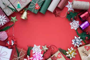 Noel tatili arkaplanının üstündeki en iyi manzara. Kırmızı arka planda köknar dalları, kurdele, fiyonk ve hediye kutusu süslemeleri olan kompozisyon. Kış, Noel, yeni yıl konsepti. Düz yat, boşluğu kopyala.