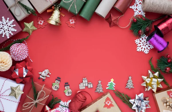 Noel tatili arkaplanının üstündeki en iyi manzara. Kırmızı arka planda köknar dalları, kurdele, fiyonk ve hediye kutusu süslemeleri olan kompozisyon. Kış, Noel, yeni yıl konsepti. Düz yat, boşluğu kopyala.