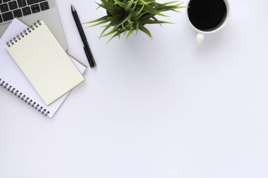 Beyaz ofis masasının üstünde klavye, defter ve kahve fincanı ve diğer ofis malzemeleri. İş ve finans kavramı. Çalışma yeri, boş kopya alanı olan düz uzanma.
