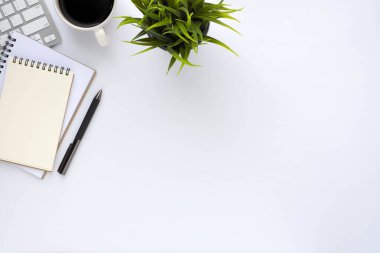 Klavyeli beyaz ofis masası, defter ve kahve fincanı diğer ofis malzemeleriyle dolu. İş ve finans kavramı. İşyeri, boş fotokopi alanı olan düz bir yer. Üst görünüm