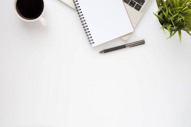 Beyaz ofis masasının üstünde klavye, defter ve kahve fincanı ve diğer ofis malzemeleri. İş ve finans kavramı. Çalışma yeri, boş kopya alanı olan düz uzanma.