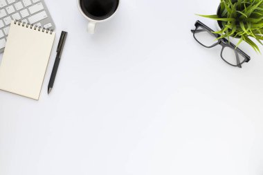 Beyaz ofis masasının üstünde klavye, defter ve kahve fincanı ve diğer ofis malzemeleri. İş ve finans kavramı. Çalışma yeri, boş kopya alanı olan düz uzanma.