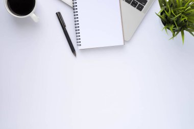 Beyaz ofis masasının üstünde klavye, defter ve kahve fincanı ve diğer ofis malzemeleri. İş ve finans kavramı. Çalışma yeri, boş kopya alanı olan düz uzanma.