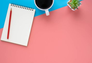 Açık okul defterinin en üst görüntüsü boş sayfalar ve mavi ve pembe arka planda kahve fincanı olan kalem. Düz yatış, yaratıcı çalışma alanı ofisi. Kopyalama alanı olan iş veya eğitim kavramı.