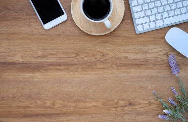 Klavye, kahve fincanı ve not defteriyle ahşap ofis masasının üstü, ekipman ofis malzemeleriyle dolu bir telefon. İş ve finans kavramı. Çalışma yeri, boş kopya alanı olan düz uzanma.