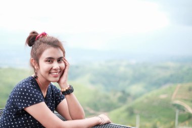 Mutlu gülümseyen Asyalı genç bayanın özgün portresi kameraya bakıyor. Balkonda fotokopi çekilen bir yerde dinleniyor. Seyahat ve Yaşam Tarzı kavramı.