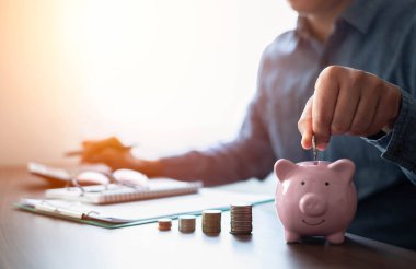 Para destesiyle pembe kumbaraya bozuk para koyarken çekilen fotoğraf büyümeyi hızlandırıyor. Planlama aşaması, gelecek için para biriktirme, emeklilik fonu. Yatırım-finans hesapları kavramı.