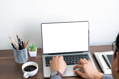 Bir adamın elinin bileğinde dizüstü bilgisayarın boş ekranının klavyesini kullanarak saat vardır. Ofisteki masada iş yapıyor. Yatırım finansmanı muhasebe konsepti. kopyalama alanı ile.