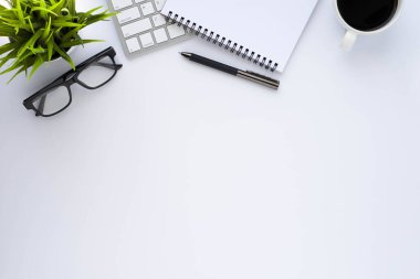 Beyaz ofis masasının üstünde klavye, defter ve kahve fincanı ve diğer ofis malzemeleri. İş ve finans kavramı. Çalışma yeri, boş kopya alanı olan düz uzanma.