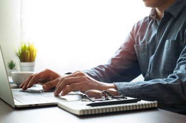 Ofis masasındaki dizüstü bilgisayarın klavyesini kullanan bir adamın yakın plan fotoğrafı. Ofiste fotokopi alanında çalışıyor. Yatırım finansmanı muhasebe kavramı.