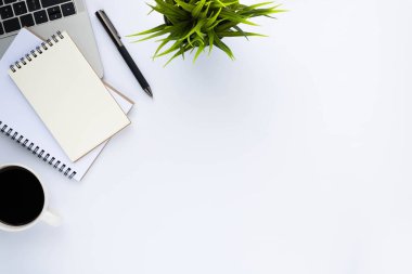 Beyaz ofis masasının üstünde klavye, defter ve kahve fincanı ve diğer ofis malzemeleri. İş ve finans kavramı. Çalışma yeri, boş kopya alanı olan düz uzanma.