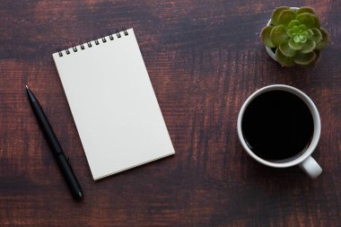 Boş sayfaları olan açık okul defterinin en üst görüntüsü, tahta masa arkaplanına not almak için kahve fincanı ve kalem. Düz yatış, yaratıcı çalışma alanı ofisi. Kopya alanı ile işletme eğitimi kavramı.