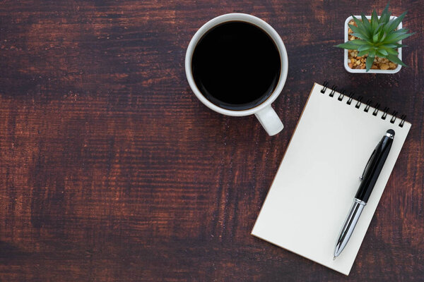 Вид сверху открытой школьной тетради с бланками, чашкой кофе и ручкой для записи заметок на фоне деревянного стола. Плоский, креативный рабочий кабинет. Концепция бизнес-образования с копированием пространства.