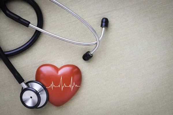 Black stethoscope, red heart with cardiogram for check-up on table background. Stethoscope equipment of doctor medical use to diagnose heartbeat. World heart day. health care and cardiology concept.