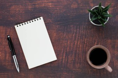 Boş sayfaları olan açık okul defterinin en üst görüntüsü, tahta masa arkaplanına not almak için kahve fincanı ve kalem. Düz yatış, yaratıcı çalışma alanı ofisi. Kopya alanı ile işletme eğitimi kavramı.